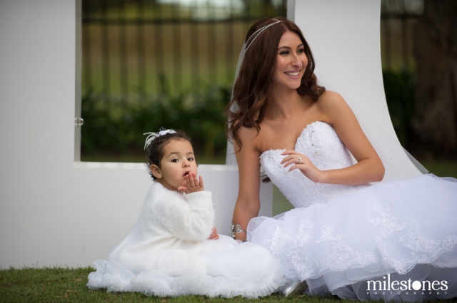 Bride and flower girl sitting on grass